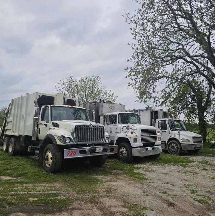 Three Dunhams trash collection trucks parked together outdoors